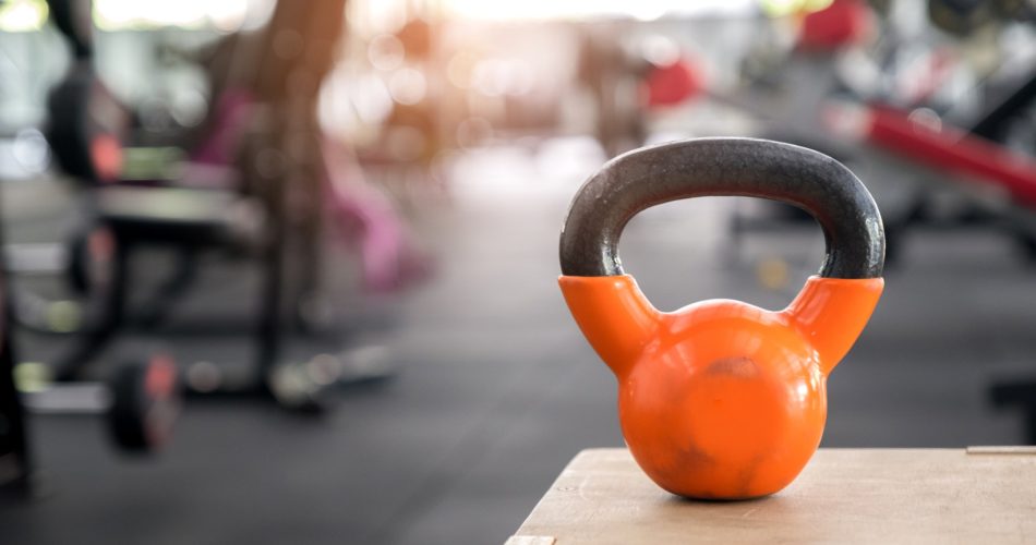 Orange kettlebell put on a wooden crate.