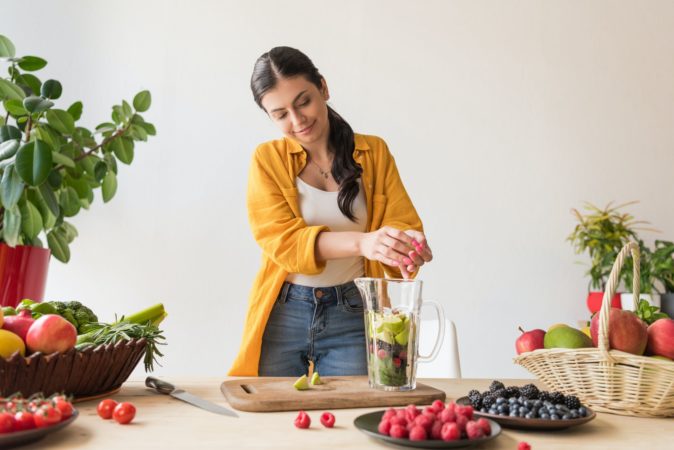 portrait of young woman preparing detox drink at home