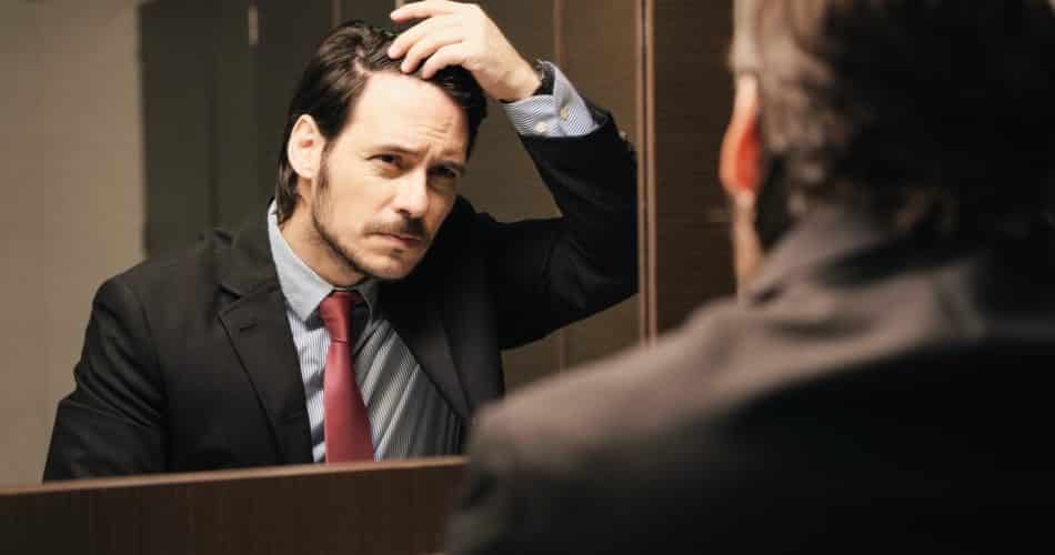 Worried Hispanic Business Man Looking At Hairline In Office Restrooms