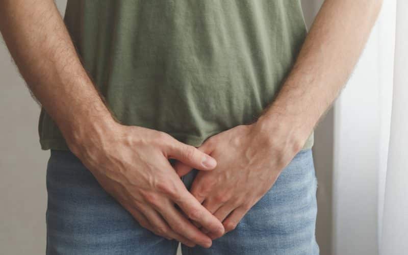 Man cover his groin by hands. Men's health. Urology problems male