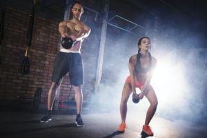 Fit couple practicing with kettlebell