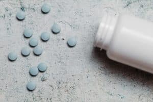 Blue pills and canister on concrete background