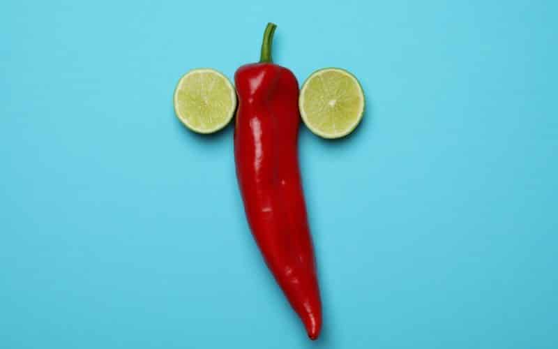 Chili pepper and lime halves on blue background