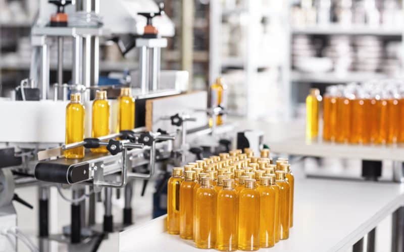 Cosmetics factory. Bottling line filled with yellow shampoo. Automated process on factory. Line of b