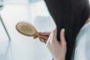 cropped shot of young brunette woman holding hairbrush, hair loss concept