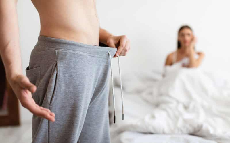 Man Looking In Pants While Woman Waiting In Bed, Cropped