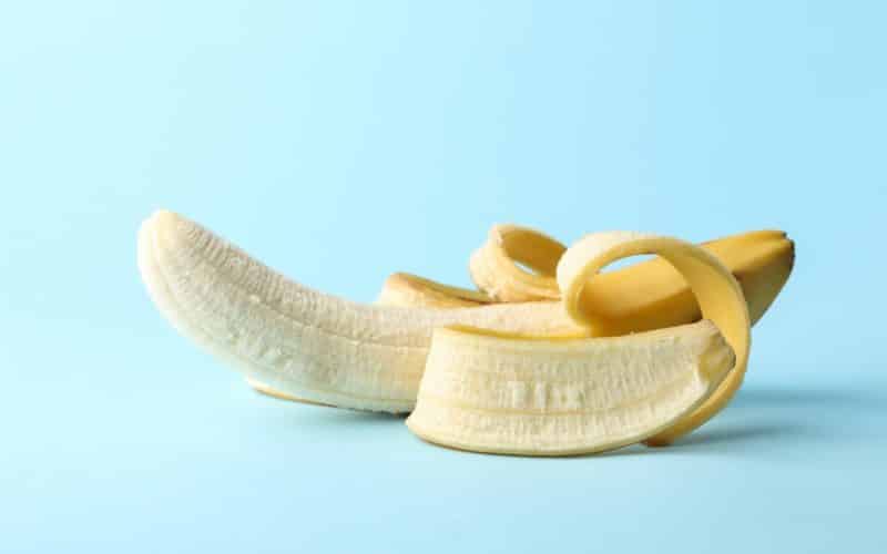 Opened banana on blue background. Fresh fruit
