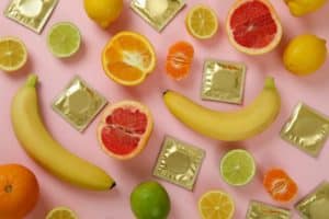 Sex concept with fruits and condoms on pink background
