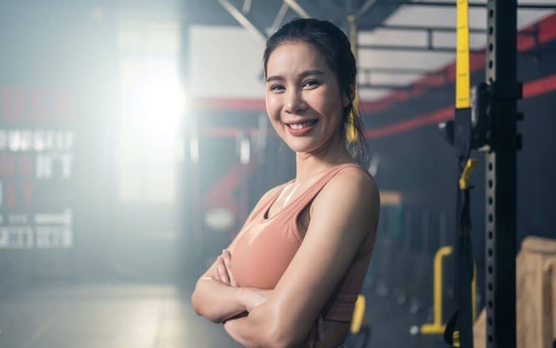 Asian girl with six packs abs in sportswear standing and crossing arms in gym or fitness